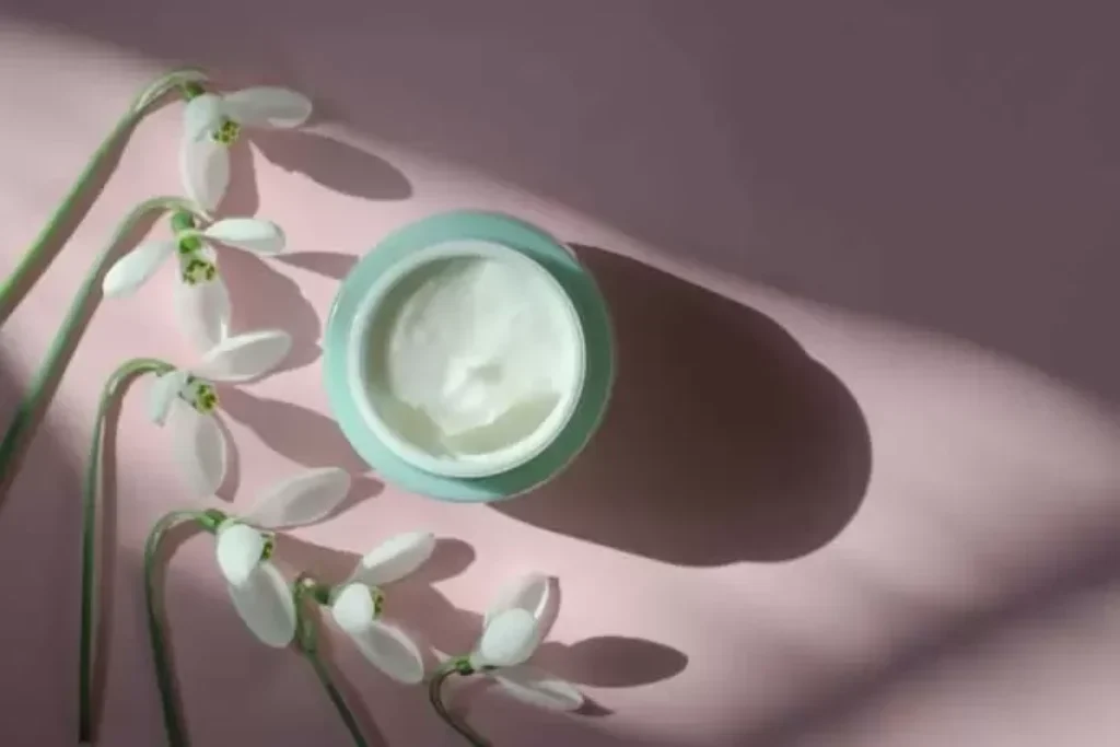 Creme em um pote e fundo rosa