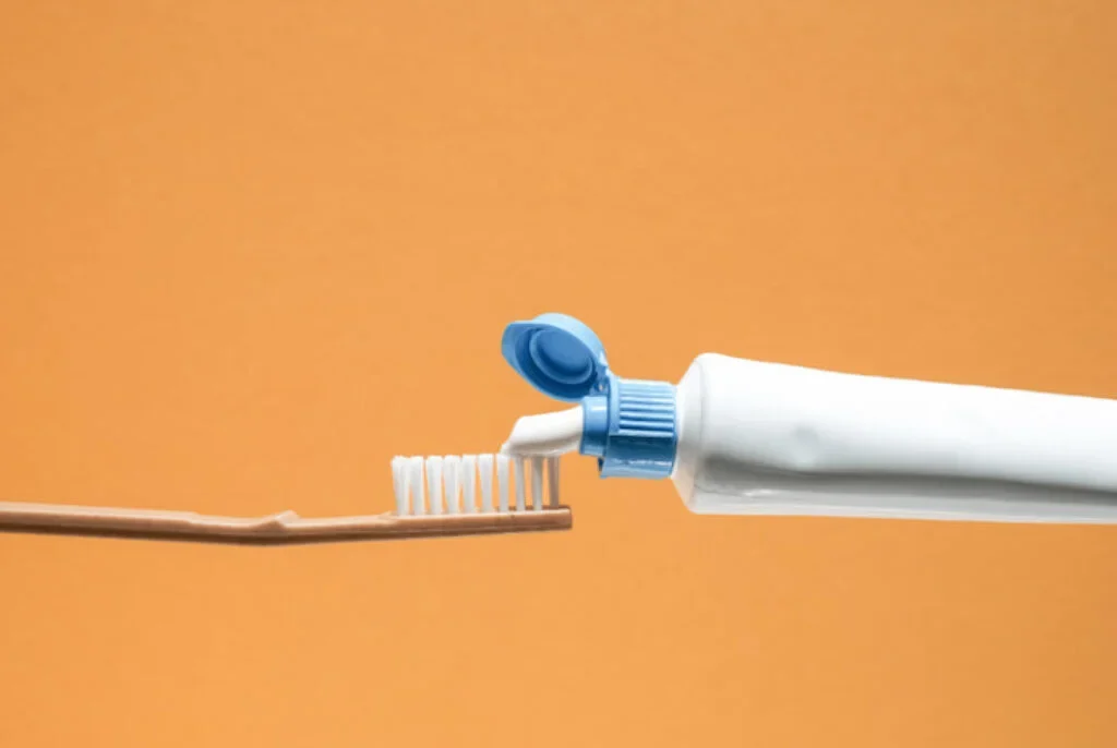 Pasta de dente, escova e fundo laranja